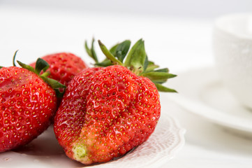 Close up. Breakfast. Appetizing juicy strawberries on white china plate. White wooden background.