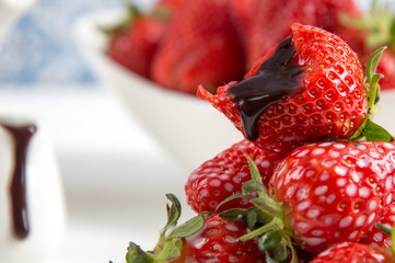 Close up, macro. French Provence. Chocolate sauce flows down on a bitten bright red strawberry.
