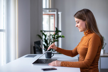 Start of a work day. Young woman opening laptop