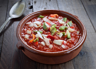clay casserole with tomato sauce and cut vegetables, in rustic wood