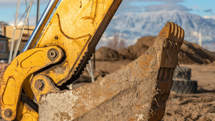 Panorama The dirty bucket and yellow arm of an excavator at a construction site © Jason