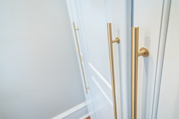 Wall of Tall White wood Painted Cabinets with modern gold handles hardware for storage