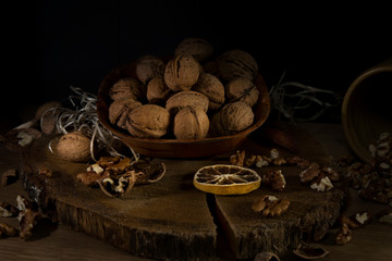 A brown plate with nuts on dark wood .Walnuts on dark background. Low-key image