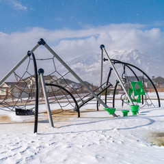Clear Square Climbing frames on a playground blanketed with snow on a sunny winter day