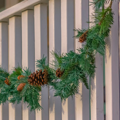 Square Traditional garland with pine cones draped on the white railing of a building