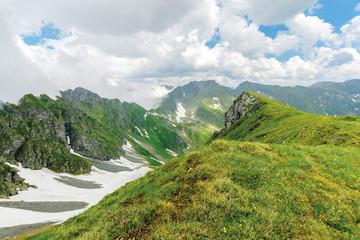 fagaras mountain ridge in summer. spots of snow on grass of steep slope. rocky tops. cloudy weather. romania landscape