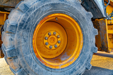 Close up of the wheel of a yellow loader parked on the road on a sunny day