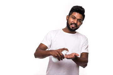 Young happy smiling man applying cream lotion on face isolated on white background