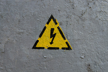 The sign of electrical hazard on a gray coarse metaic painted surface