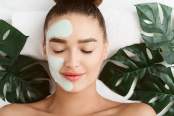 Facial Mask. Girl Lying On Table With Tropical Leaves