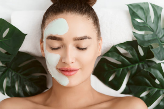 Facial Mask. Girl Lying On Table With Tropical Leaves