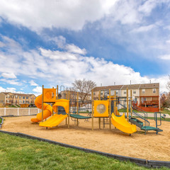 Square Colorful slides at a playground with homes and cloudy sky in the background