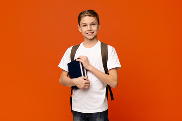 Cheerful boy with backpack holding books