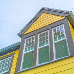 Square Home in Daybreak Utah with yellow wall and reflective glass windows against sky