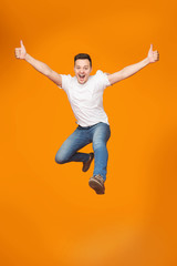 Fototapeta na wymiar Excited Young Man Jumping, Celebrating Success Over Studio Background