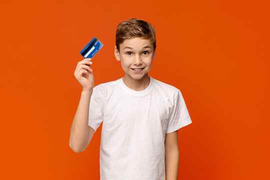 Cute Boy Holding Credit Card, Orange Studio Background