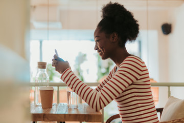 Low angle of happy African woman having rest in cafe