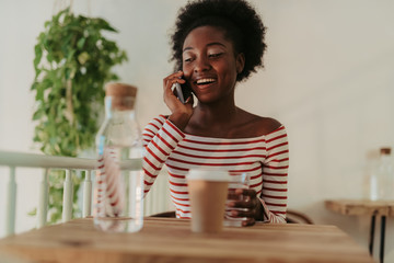 Low angle of happy African woman having rest in cafe