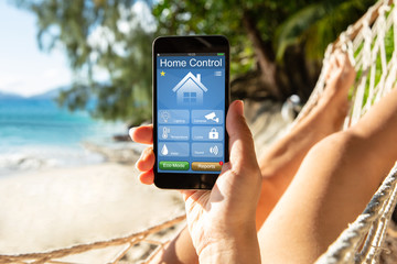 Woman Using Smart Home On Mobile Phone At Beach