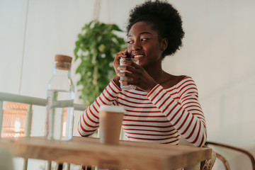 Low angle of pretty African woman having rest in cafe