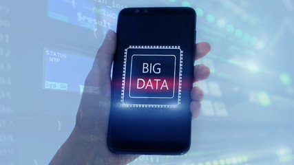 Woman Hand holding mobile phone. Server room background. Inscription on a virtual screen: Big Data. Double exposure.