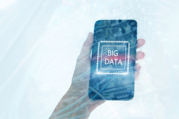Woman Hand holding mobile phone. Server room background. Inscription on a virtual screen: Big Data. Double exposure.