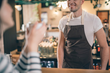 Close up of smiling male barista at the bar counter