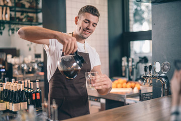 Smiling barista looking confident while pouring fresh coffee