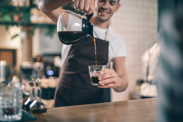 Hot black coffee pouring out of the glass jug