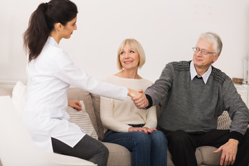 Mature Couple Welcoming Nurse During Home Visit