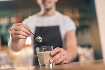 Selective focus of teaspoon near the cup of cappuccino