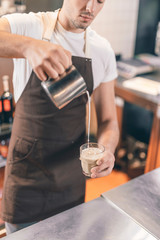 Concentrated barista making coffee with milk at work