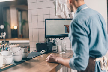 Close up of barista at the bar counter with computer by his side