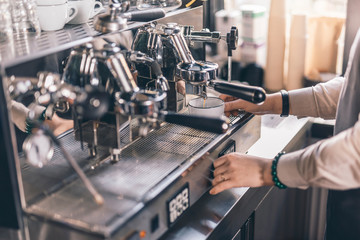 Hands of barista on the working espresso machine