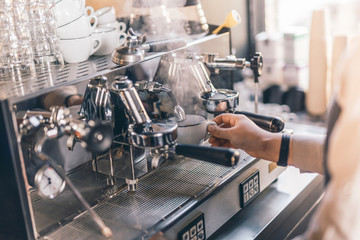 Hand of barista holding white cup and adding hot water into it