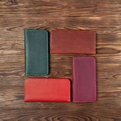Four handmade leather porte-monnaie on wooden textured background. Up to down view. Stock photo of luxury accessories.