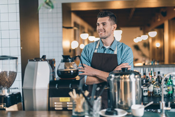 Smiling barista feeling good and smiling while standing alone
