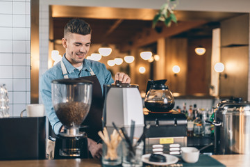 Waist up of a young barista working at the bar counter in cafe