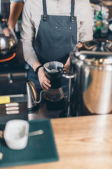 Hands of barista making pour over coffee at the bar counter