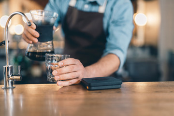 Hand putting glass on the bar counter and holding drip decanter