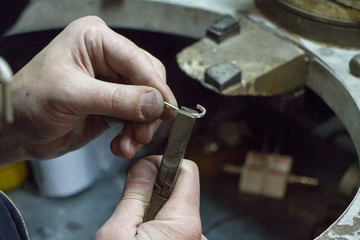 The master jeweler holds the working tool in his hands and makes jewelery at his workplace