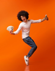 Happy african american guy dancing on tiptoes with money fans