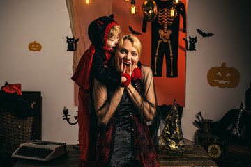 Mom and little child boy on studio near pumpkin and halloween decoration, bright emotion, laughter,...