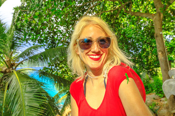 A cute Phelsuma sundbergi called La Digue day gecko on arm of a smiling tourist woman on vacation at Seychelles. Happy caucasian female enjoys with lizard, wildlife of La Digue.