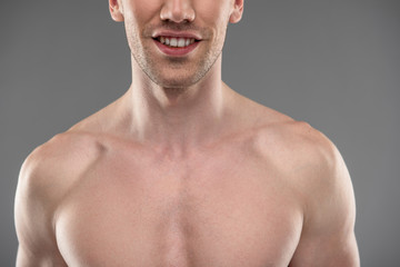 Smiling young man with stubble standing against blue-gray background