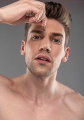Obraz premium Handsome young man plucking eyebrows with tweezers