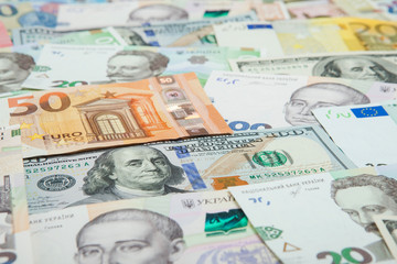Money and finances concept. One hundred dollar new bill on colorful abstract background of Ukrainian, American and euro national currency banknotes