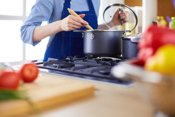 Cooking woman in kitchen with wooden spoon