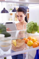 Young woman with glass of tasty healthy smoothie at table in kitchen