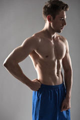 Fototapeta premium Handsome young man with perfect body standing against blue-gray background